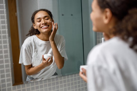 smiling-woman-applying-antiwrinkle-cream-standing-mirror-home-bathroom-beauty-procedure