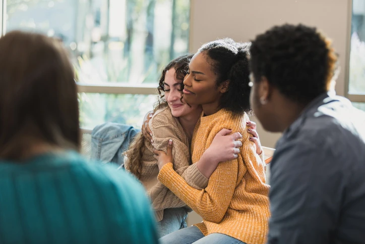 Young Women Embracing in Group Therapy Session - Maryvale